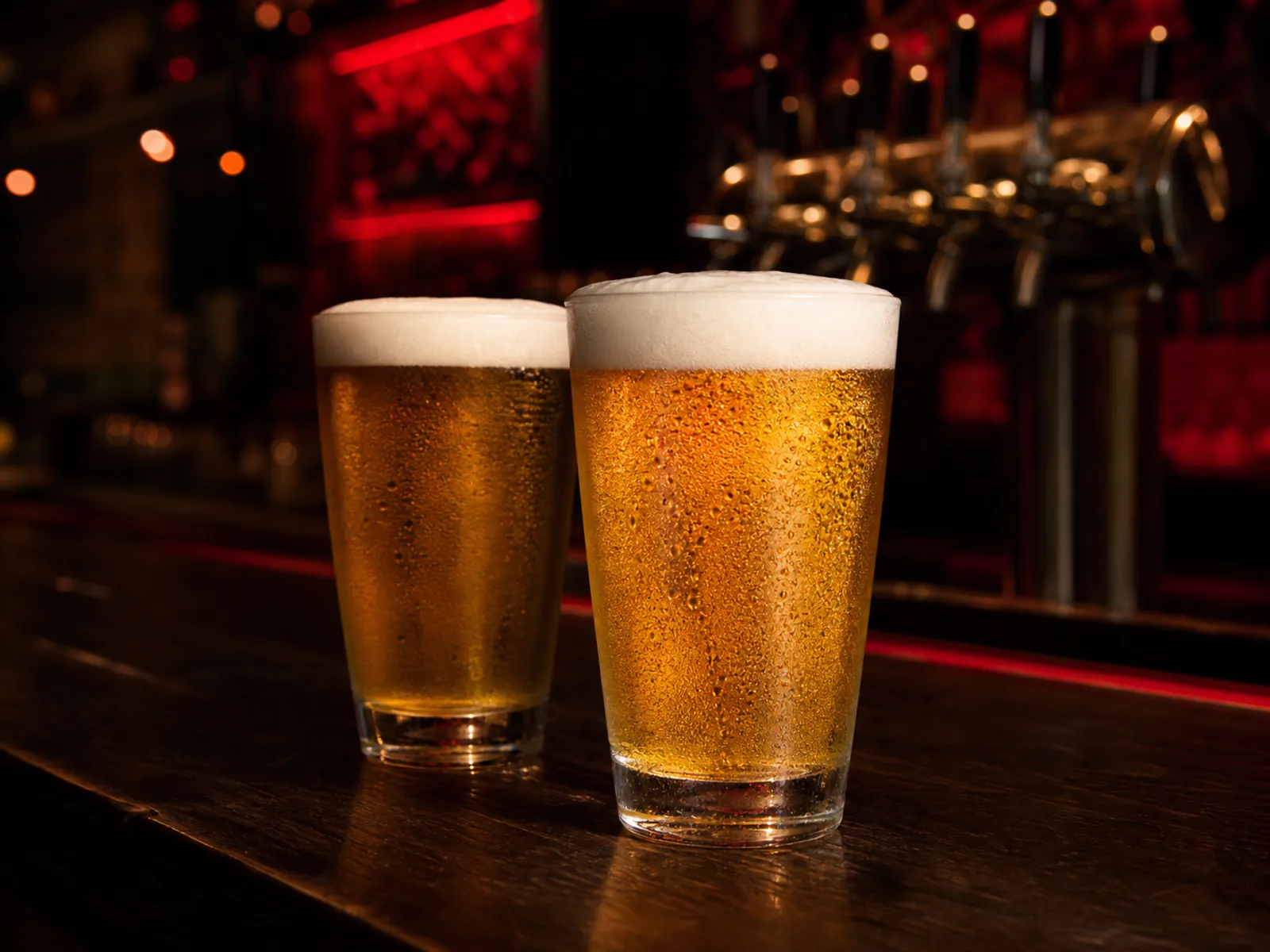 Two chilled glasses of golden draft beer on the MAD ROOSTA bar